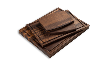 A set of four walnut cutting boards of varying sizes, stacked together, with a smooth and glossy finish. made in quebec, made in canada